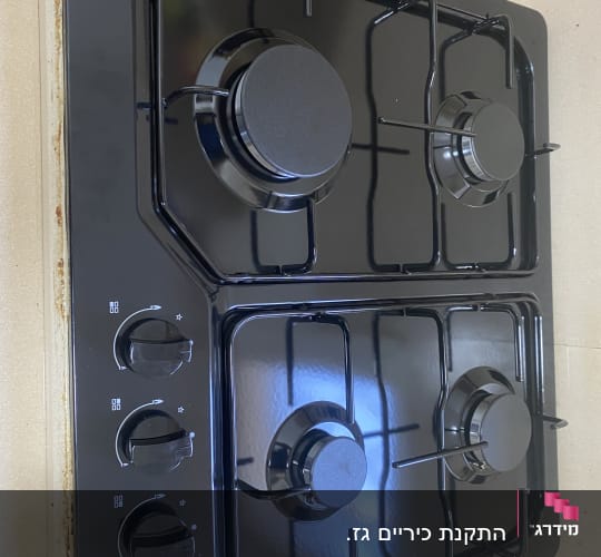 כיריים גז שחורות עם ארבעה מבערים וכפתורי שליטה